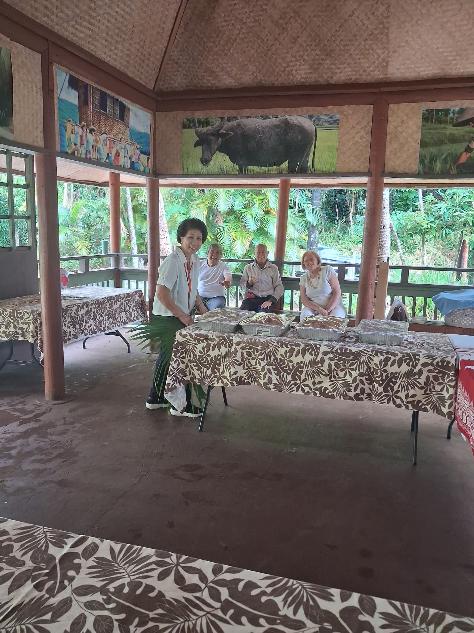 Volunteers and neighbors gathered around a shared meal inside the bahay kubo at Kepaniwai