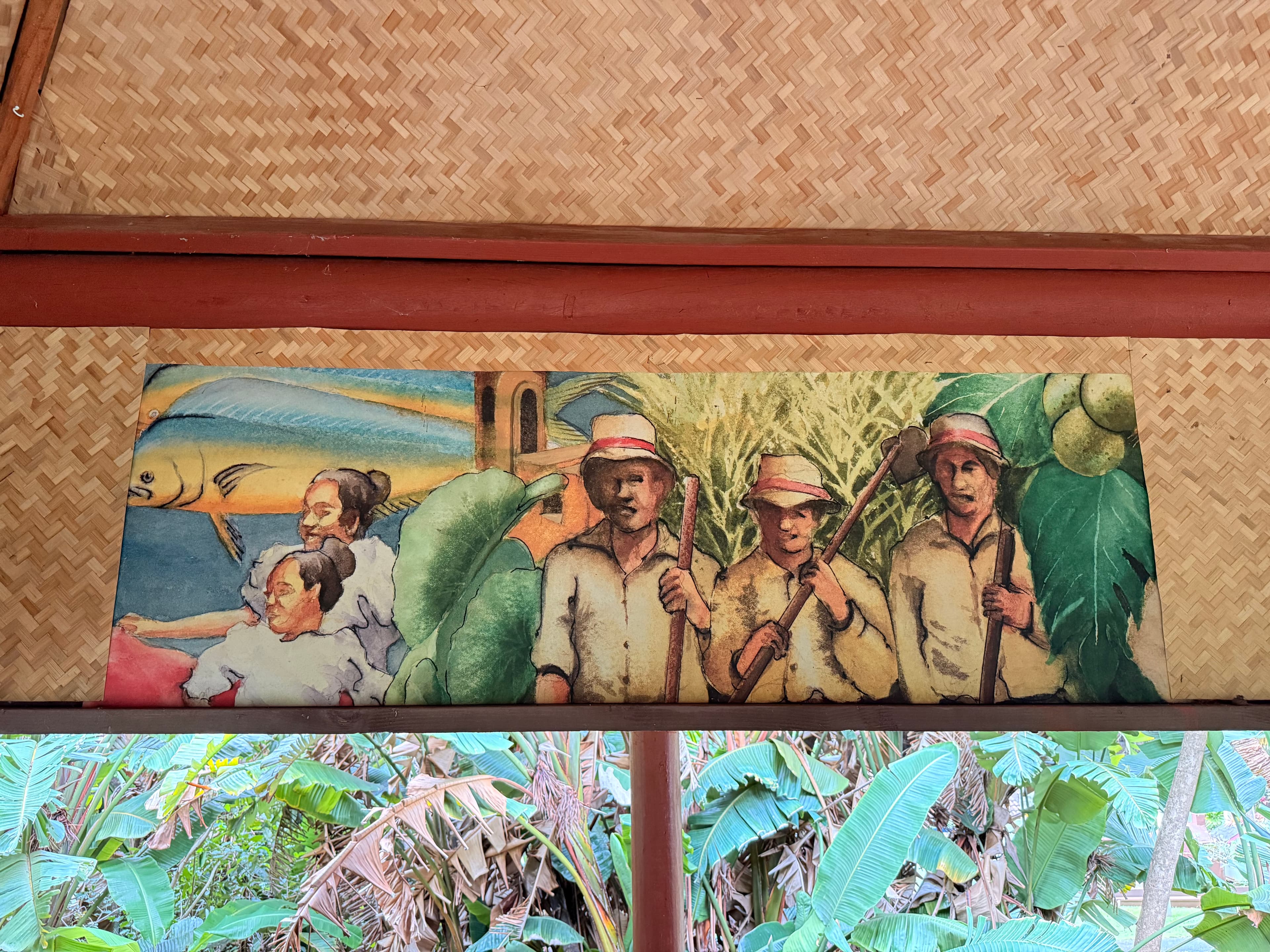 Horizontal mural of Filipino life with figures, a large fish, a church, sugarcane, and tropical plants